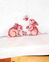 Morning dawns as these bunnies chase an elusive butterfly on these stamped cross-stitch pillowcases.